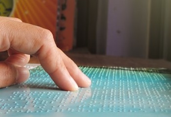A finger reading a refreshable Braille display